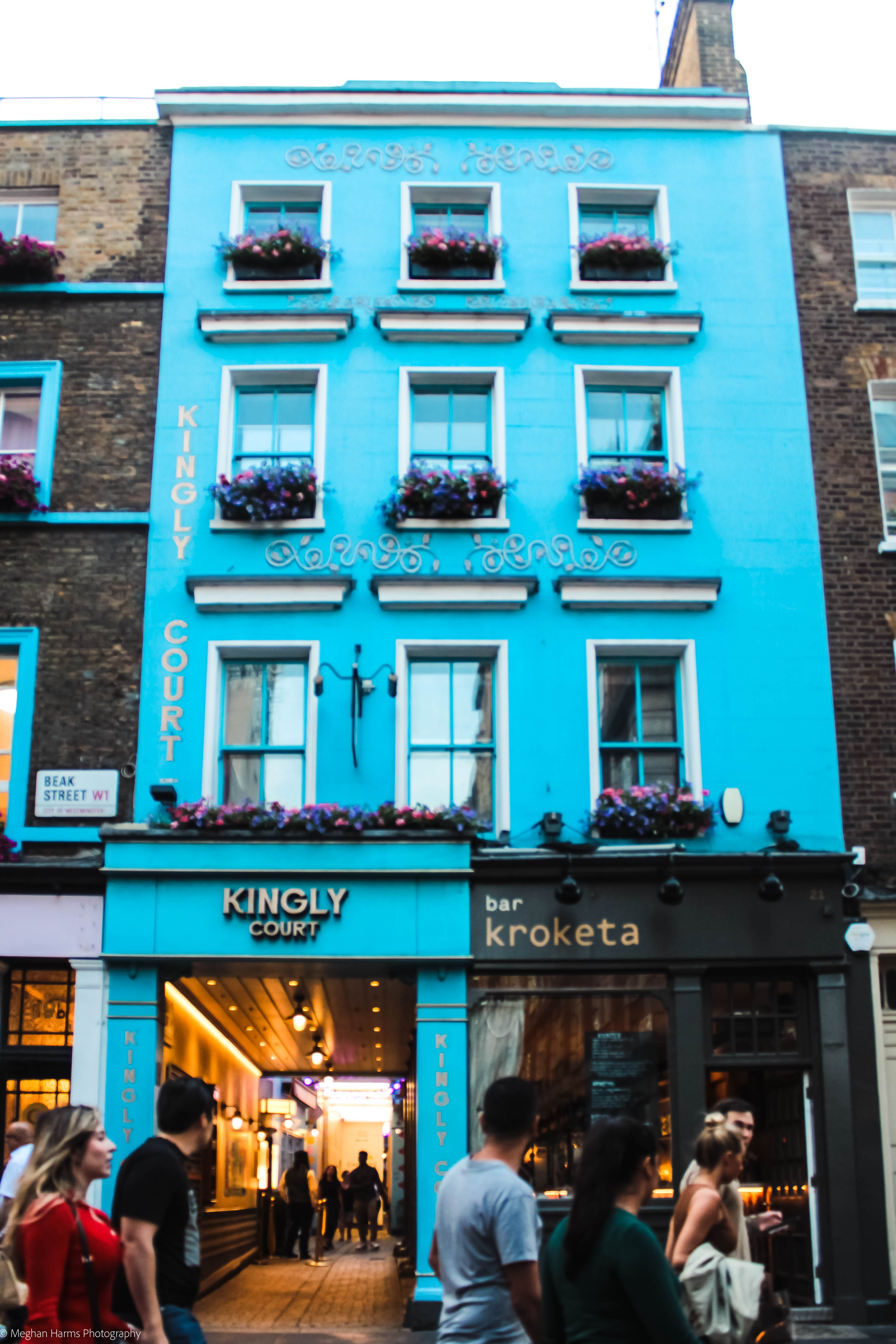 Bright blue narrow building with 9 windows and an archway to the other side of thr street