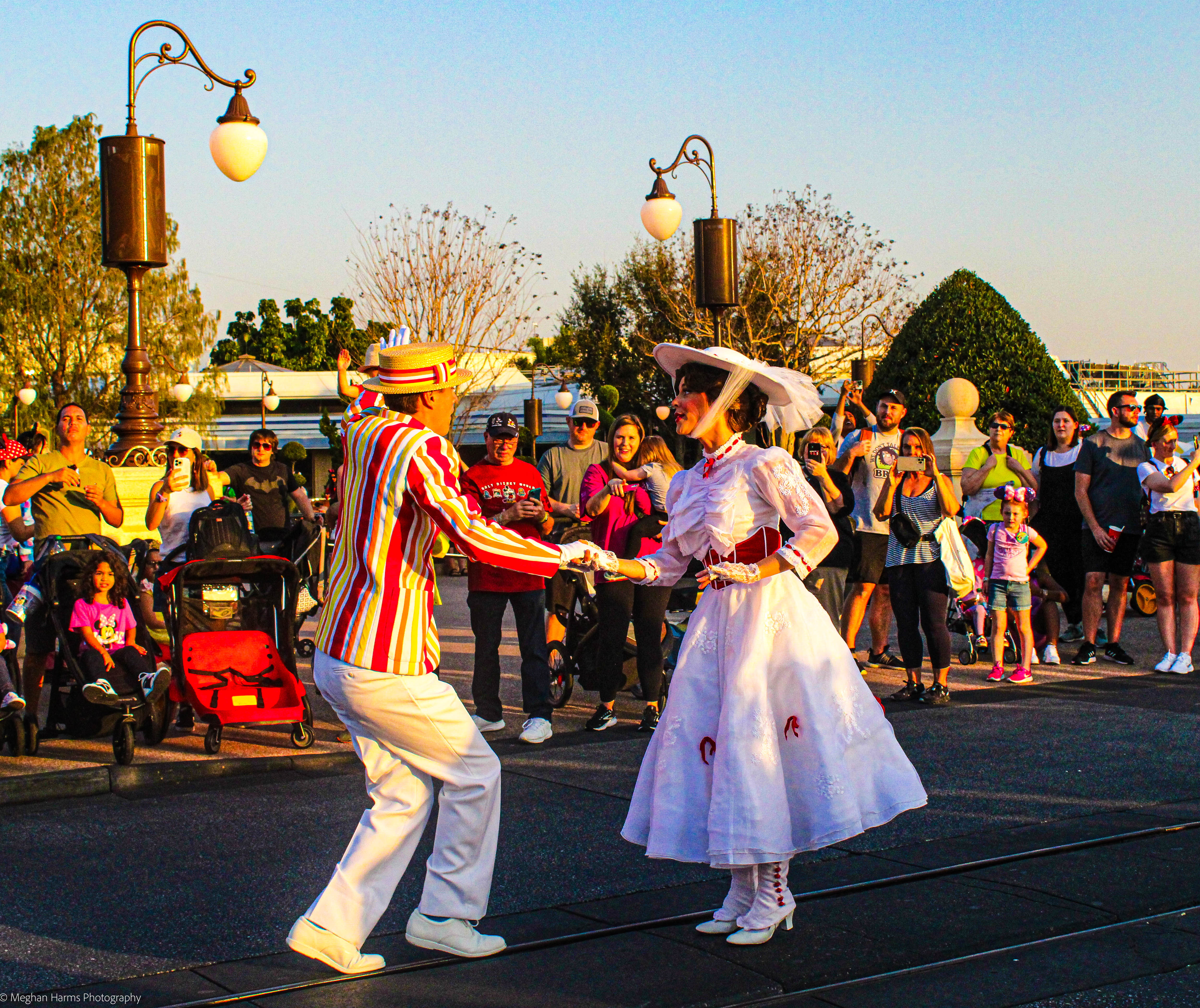 Bert, in a red, white and yellow striped suit jacket and white pants, and Mary Poppins in a white dress and big white hat standing on Main Street USA